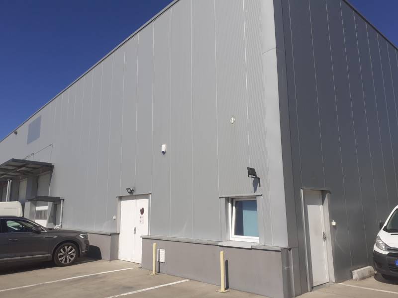 Raktárak és csarnokok a Pozsony-Ružinov Technikai utcában, parkoló autókkal a bejárat előtt.