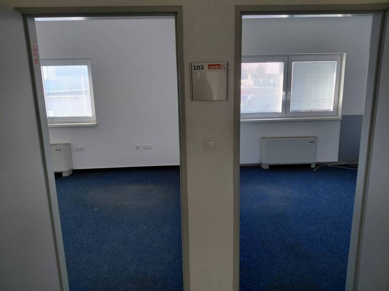 Irodák belső tere kék szőnyeggel és redőnyös ablakokkal.