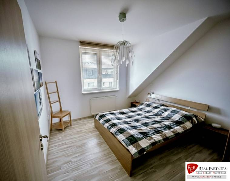 Hálószoba egy háromszobás lakásban, ággyal és fa dekorációjú padlóval.