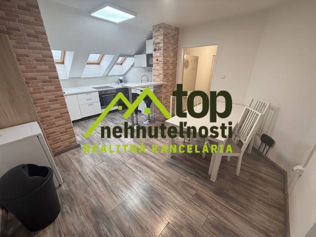 Egy egyszobás lakás belső tere fa dekoros padlóval és téglaburkolatú konyhával.