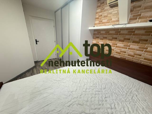 Hálószoba tégladekorációval egy egyszobás lakásban, a padlón fa hatású padlóburkolat.