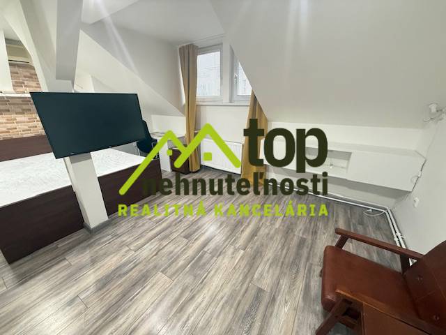 Szoba fa dekorációjú padlóval, modern televízióval és bútorokkal egy egyszobás lakásban.