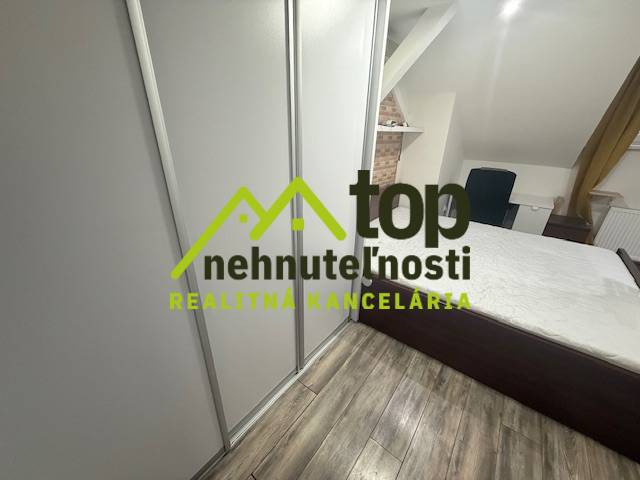 Hálószoba egy egyszobás lakásban fa dekor padlóval és beépített szekrénnyel.