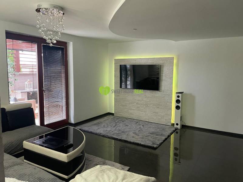 Nappali egy családi házban fényes padlóval és falra szerelt TV-vel.