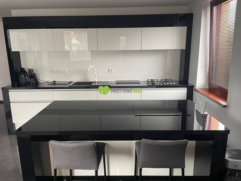 Konyha családi házban fényes fekete-fehér bútorokkal és étkezőpulttal.