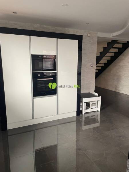 Konyha egy családi házban fényes fekete padlóval és fehér készülékekkel.