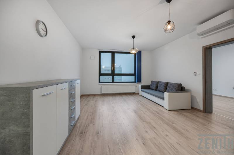 Nappali egy kétszobás lakásban kanapéval és fa dekor padlóval.