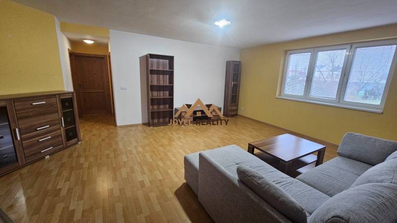 Nagy nappali egy háromszobás lakásban kényelmes kanapéval és fa dekorációval.