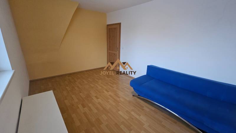 Nappali egy háromszobás lakásban, fa dekoros padlóval és kék kanapéval.