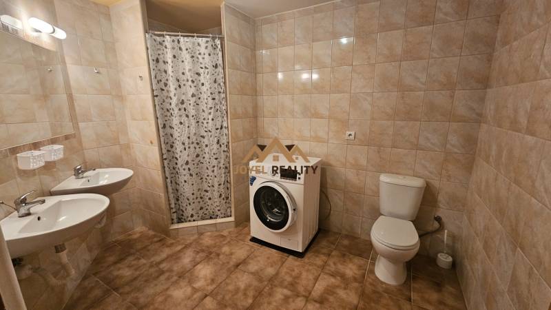 Fürdőszoba egy háromszobás lakásban zuhanyzóval, dupla mosdóval, WC-vel és mosógéppel.