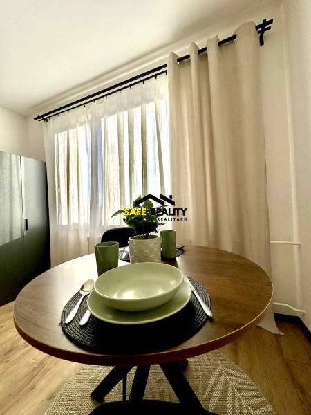 Egy egy szobás lakás egyik otthonos sarka kerek asztallal és edényekkel.