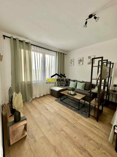 Egyszobás lakás belső tere kanapéval, asztallal és fa dekorációjú padlóval.