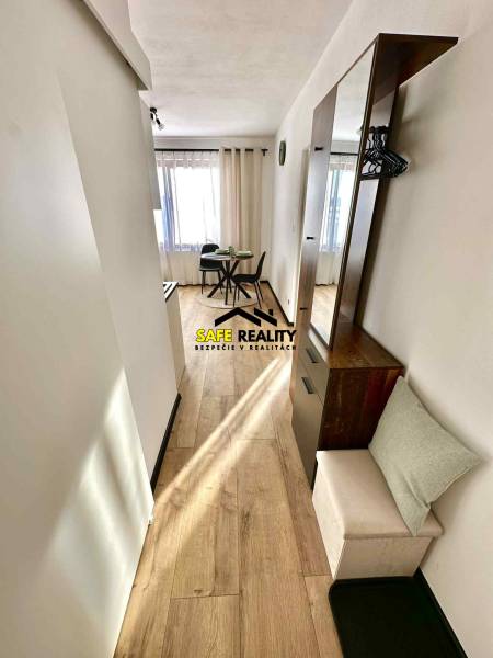 Világos belső tér étkezőasztallal és fa dekorációjú padlóval egy egyszobás lakásban.