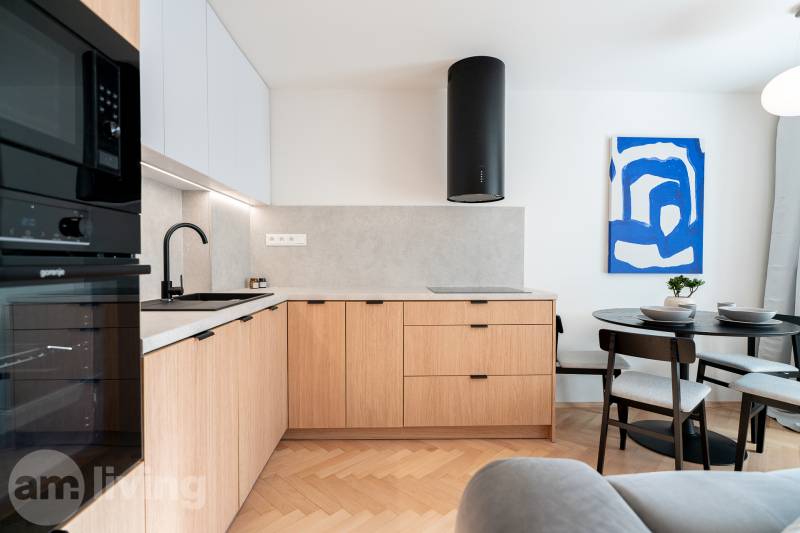 Konyha fa mintázatú padlóval, fa szekrényekkel és étkezőasztallal egy háromszobás lakásban.