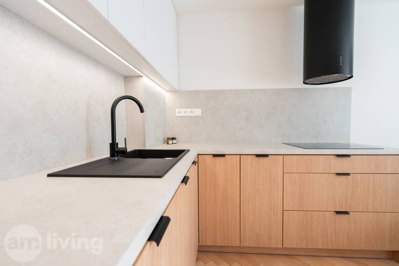 Konyhapult egy háromszobás lakásban, fa mintázatú padlóval és fekete mosogatóval.