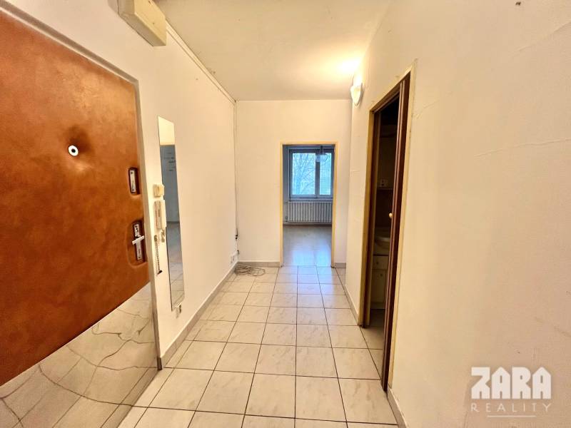 Folyosó egy 3 szobás lakásban csempével és bejárati ajtóval.