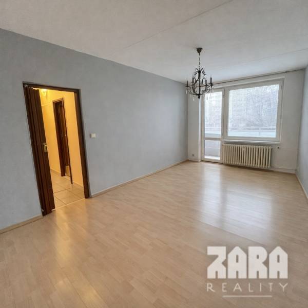 Szoba fa dekorációs padlóval és csillárral egy háromszobás lakásban.