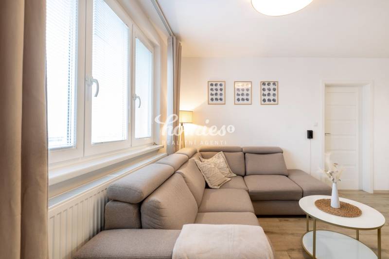 Nappali egy kétszobás lakásban kényelmes kanapéval és faldekorációkkal.