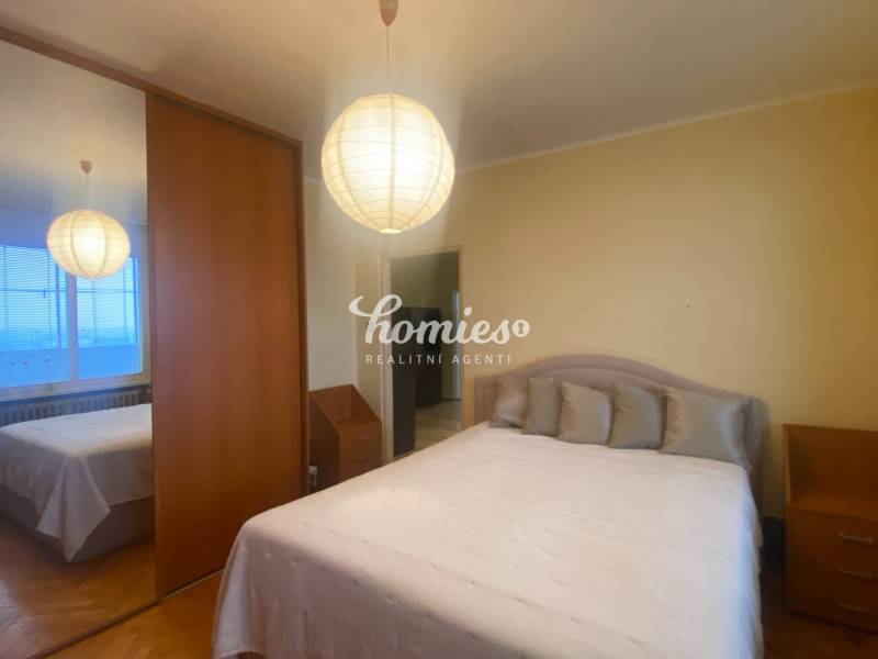 Hálószoba egy háromszobás lakásban szekrénnyel, ággyal és fa dekorációjú padlóval.