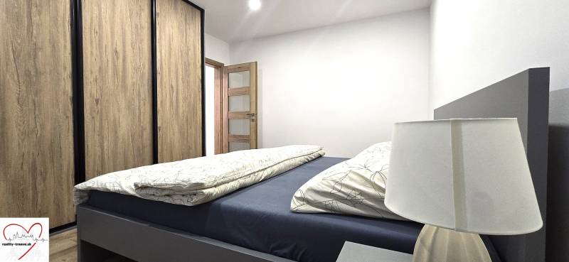 Hálószoba ággyal, fa dekorációjú szekrénnyel és lámpával egy háromszobás lakásban.