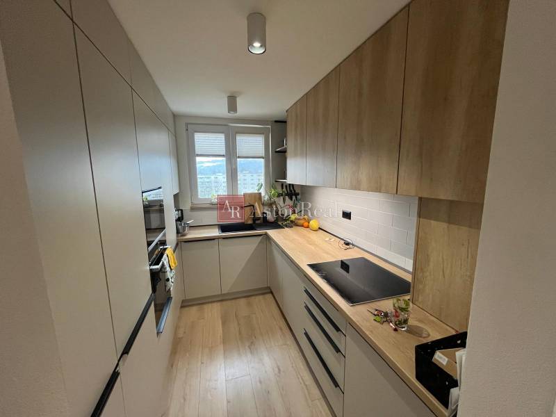 Konyha egy 4 szobás lakásban, konyhabútorral, háztartási gépekkel és fa dekorációjú padlóval.