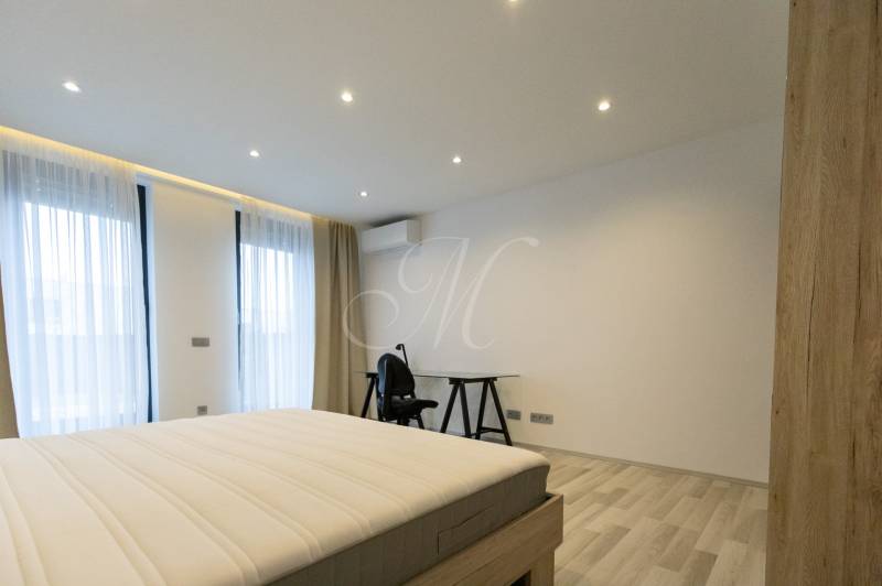 Hálószoba egy kétszobás lakásban ággyal, asztallal és fa dekorációjú padlóval.