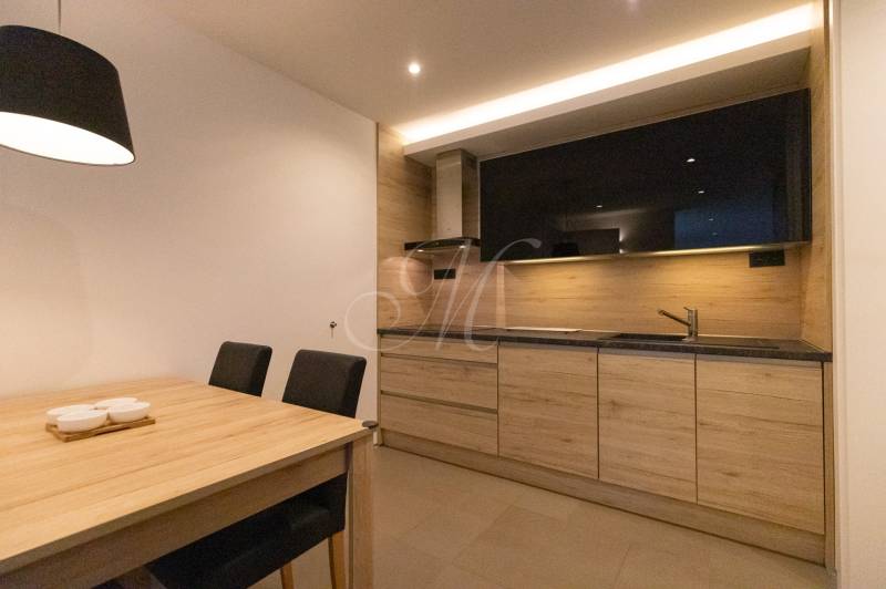 Két szobás lakás konyhája minimalista dizájnnal, fa dekorációval és étkezőasztallal.