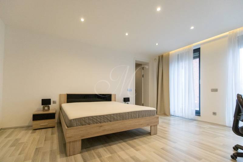 Hálószoba egy kétszobás lakásban ággyal, éjjeliszekrénnyel és fa dekorációjú padlóval.