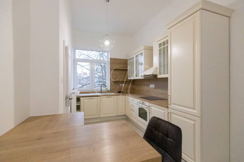 Konyha egy háromszobás lakásban, fa dekor padlóval és klasszikus konyhaszekrényekkel.