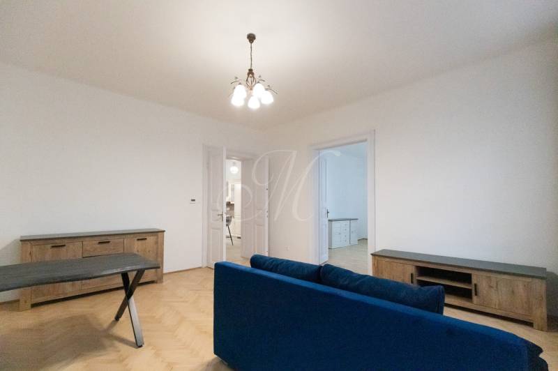 Nappali egy háromszobás lakásban, fa dekorációjú padlóval és kék kanapéval.