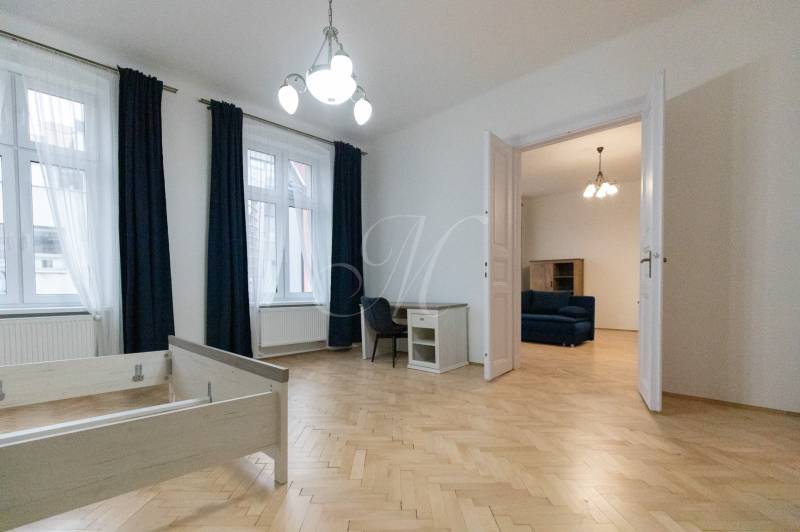 3 szobás lakás belső tere fa dekorációjú padlóval, bútorokkal és csillárral.