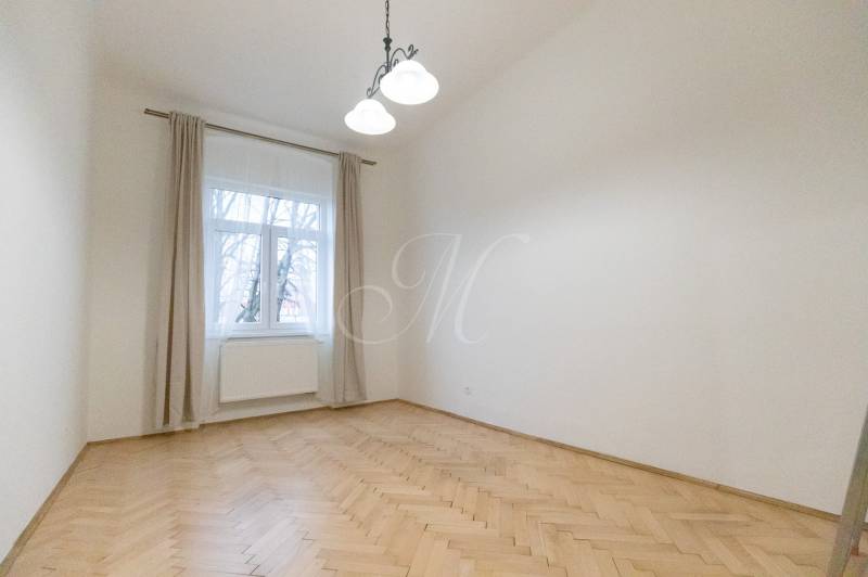 Szoba egy háromszobás lakásban, fa dekorációjú padlóval és nagy ablakkal.