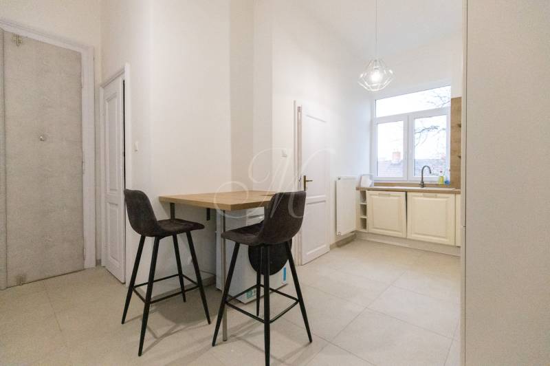 Konyha egy háromszobás lakásban bárpulttal, két székkel és nagy ablakkal.