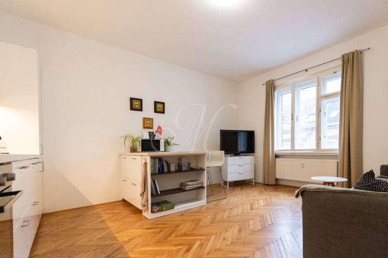 Nappali egy kétszobás lakásban világos bútorokkal és fa dekorációjú padlóval.