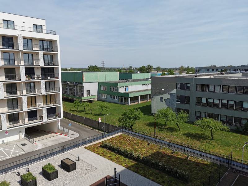 Kilátás a lakóépületekre és a zöldterületre a pozsonyi-Rača Eduarda Wenzl utcában, jobbra garázsok.