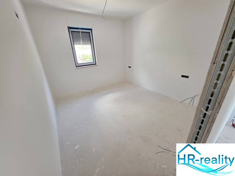 Világos szoba fehér falakkal és HR-reality márkájú ablakkal a Rekreációs apartmanban.