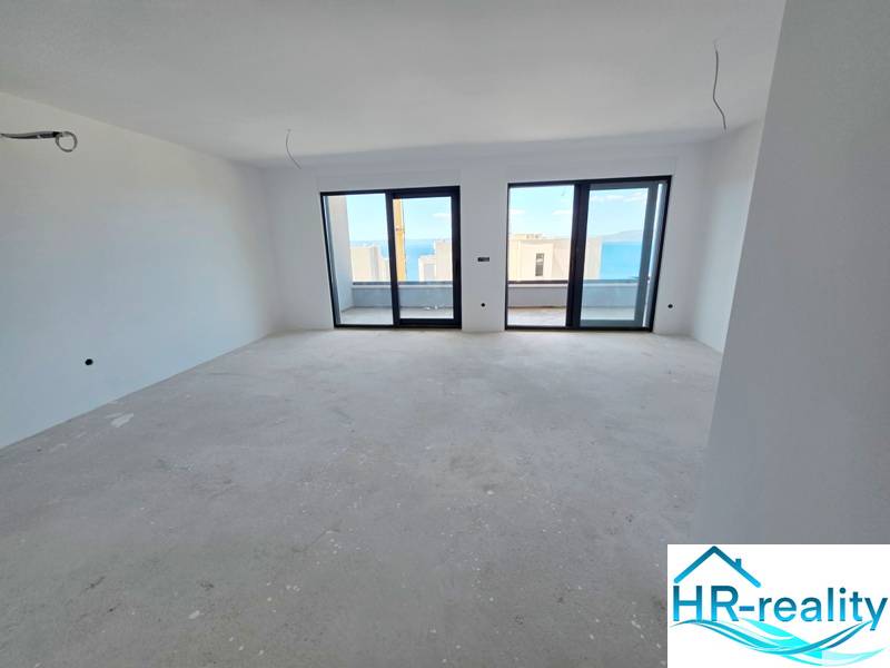 Nyaraló apartman belső tere nagy ablakokkal, kilátással a tengerre.