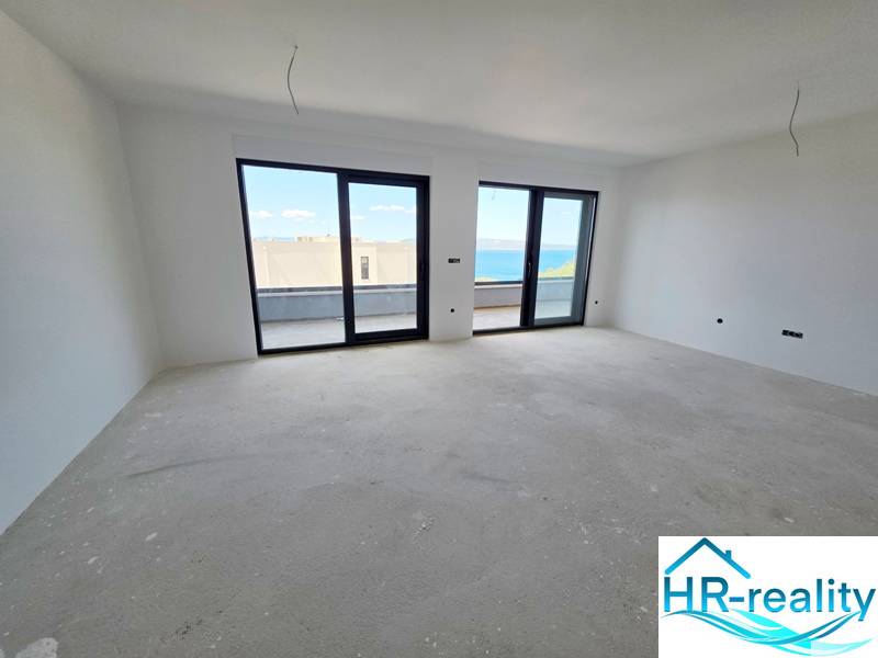 Világos szoba egy üdülő apartmanban, nagy ablakokkal, kilátással a tengerre.