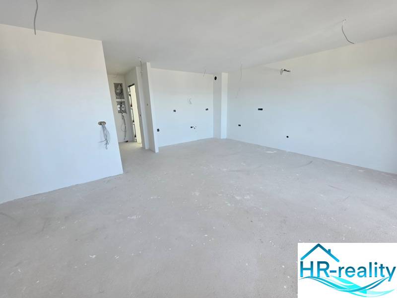 Nyaraló apartman tiszta fehér falakkal és tágas, fa dekorációjú padlóval.