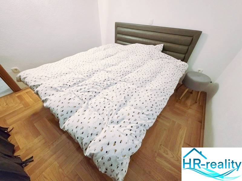 Rekreációs apartman ággyal, fa dekorációjú padlóval és kis éjjeliszekrénnyel.