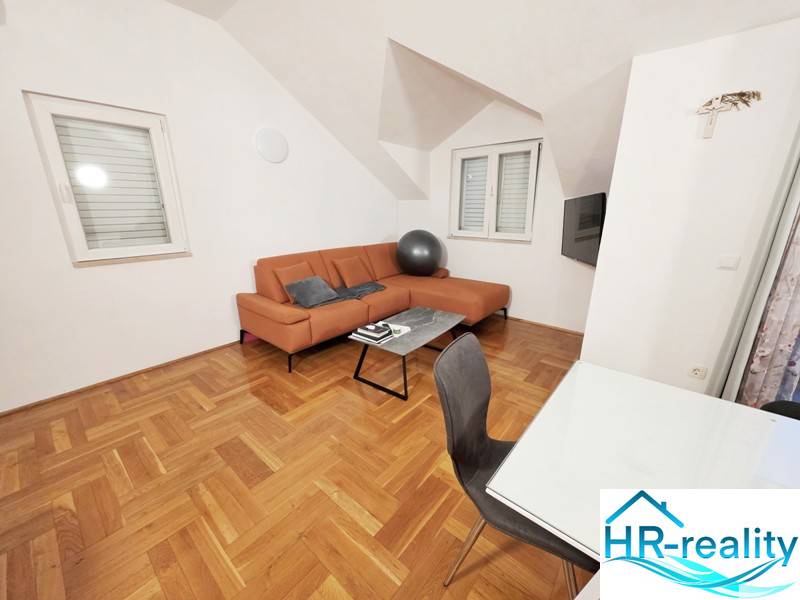 Nyaraló apartman narancssárga kanapéval és fa dekorációjú padlóval.