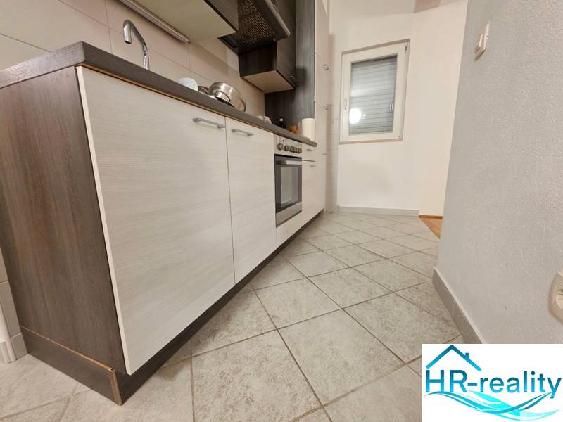 Konyha egy nyaraló apartmanban csempével és modern konyhabútorral, sötét szekrényekkel.