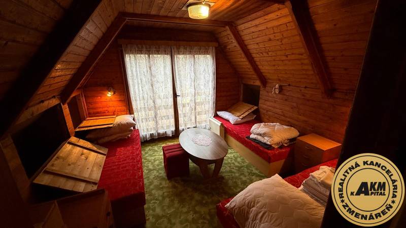 A faház belső tere fa burkolattal, három ággyal és egy kerek asztallal.