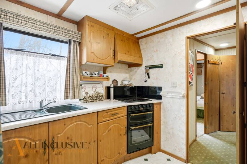 Chata konyhája fa dekorációval, tűzhellyel és otthonos hangulattal.