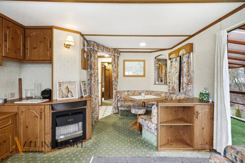 Egy kunyhó belseje vintage bútorokkal és szőnyeggel, természetes fénnyel megvilágítva.