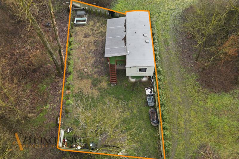 A gabčíkovi ház melletti kert, amelyet narancssárga vonal határol, fákkal körülvéve.