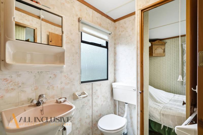 Fürdőszoba a házban mosdóval, tükörrel, WC-vel és kilátással a hálószobára.