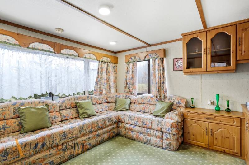 A sarokkanapéval, dekoratív függönyökkel és fa szekrényekkel berendezett házikó belseje.