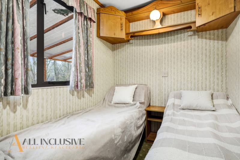 Két ágy dekorációkkal és fa szekrényekkel a kunyhó belső terében.