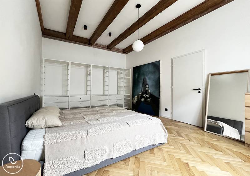 Hálószoba egy kétszobás lakásban fa gerendákkal és tükörrel a Vajnorská utcában.